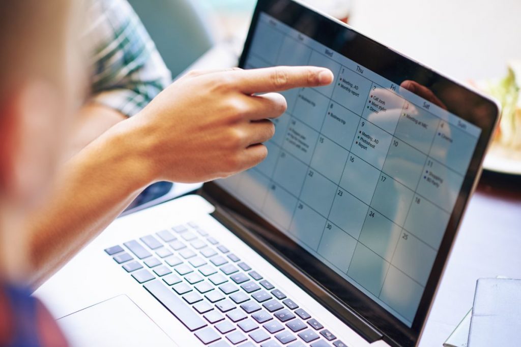 Close-up image of production team discussing working calendar for a month on laptop screen