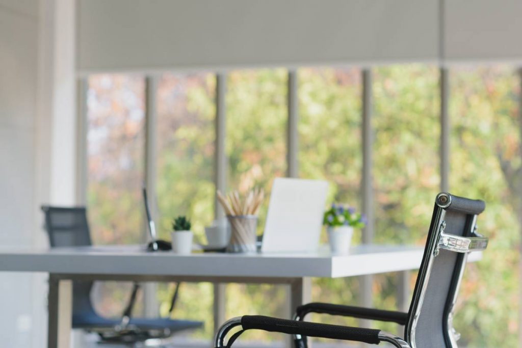 Modern design office room with couple of chairs and 1 table and pencil, notebook, small vase, pen, and coffee cup on table, Nature outside window background